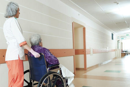 Nurse pushing a patient down a hallwayy in a wheelchair